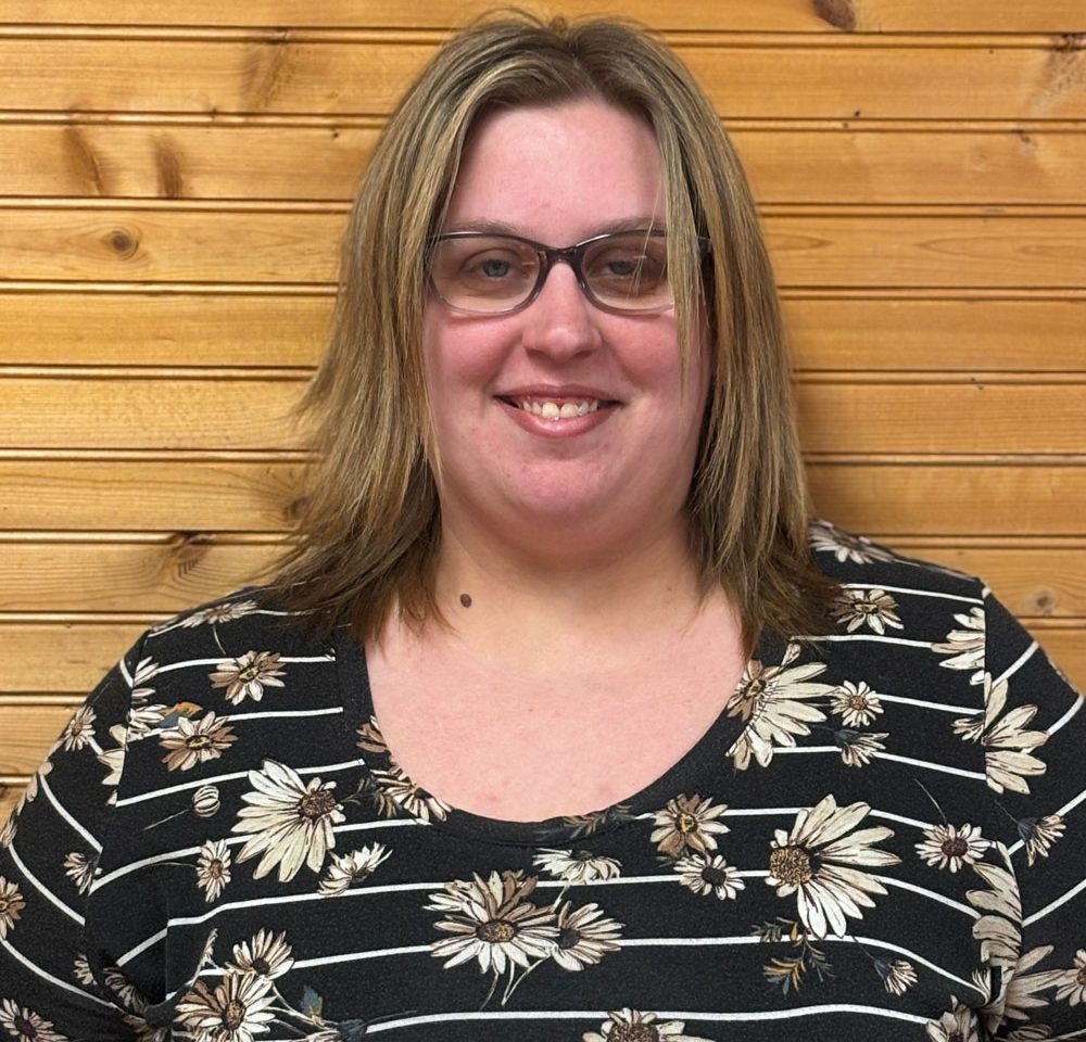 Town of Hartsville Town Clerk Ashley Gibson wearing a black shirt with white daisies in front of a wood wall