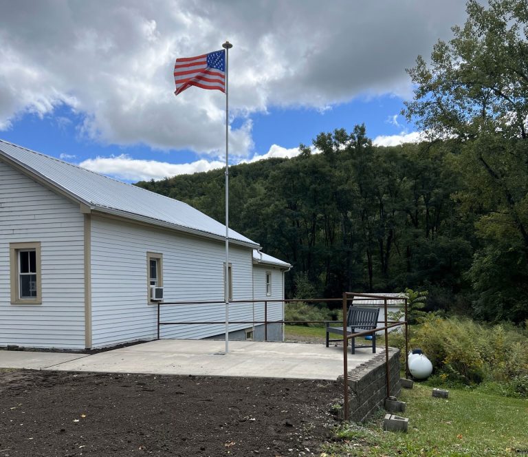 Town of Hartsville memorial area for Darold "Buddy" Getman, paved area with flag pole flying the American flag next to the Town of Hartsville office