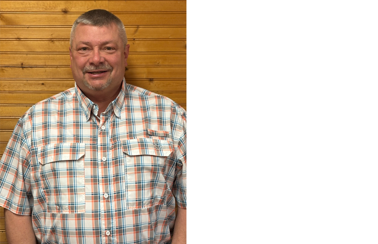 Town of Hartsville Town Supervisor David Gerhard wearing a white, grey, orange and blue checkered flannel standing in front of a wood wall.