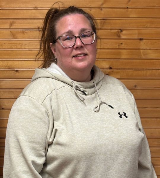 Town of Hartsville Board Member Misti Carbone wearing a grey hooded sweatshirt with a black under armor logo and standing in front of a wood wall